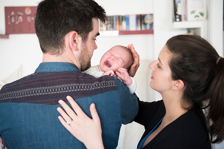 papá cargando a su bebé y mamá acariciando al bebé
