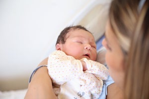 Mamá cargando a su bebé realizando cuidados después de la cesárea