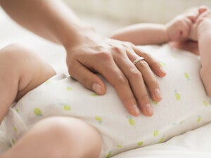 Mamá masajeando la pancita de su bebé con molestias digestivas como cólicos, reflujo, gases y estreñimiento.