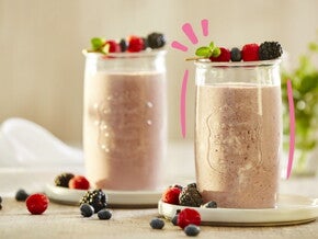 Vaso de smoothie de frutos rojos con frutos encima 