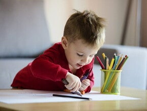 Niño pequeño coloreando una hoja blanca. Aprendiendo colores.