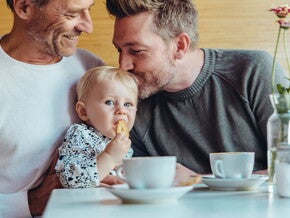 Niña comiendo galletas para bebés con su papá y abuelo