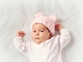 Bebé de dos meses acostada sobre la cama.