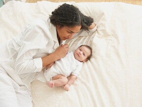 Mamá acostada con su bebé de tres meses