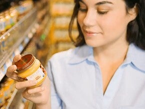Mujer leyendo etiqueta nutricional con un frasco de colado para bebes