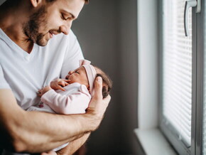 Papá alzando su bebé y revisando los granitos de su cara