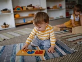 Actividad Montessori para bebés de 8 a 12 meses utilizando un rompecabezas de formas para estimular la coordinación, la exploración y la autonomía.