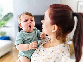 Mamá cargando a su bebé que tose. Asma en niños y bebés.
