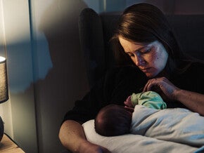 Mamá acostada dando de amamantar a su bebé, preocupada porque no come