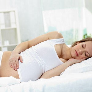 Posturas para dormir durante el embarazo Mujer probando posturas para dormir durante el embarazo