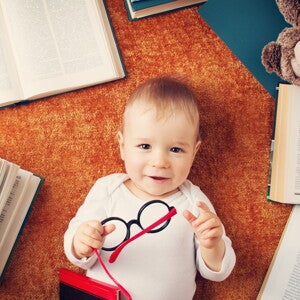 Niño de un año con anteojos rodeado de libros Niño de un año con anteojos rodeado de libros