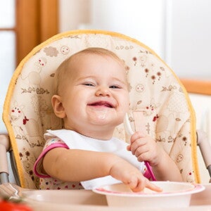 Papilla-de-verduras-y-pollo bebe sonriendo y comiendo alimentos para bebe de 9 meses