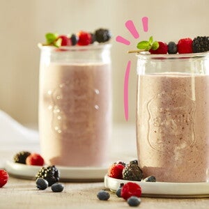 Vaso de smoothie de frutos rojos con frutos encima 