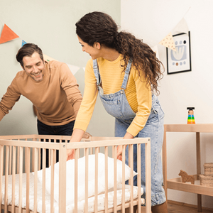 Preparate para la llegada de tu bebé con nuestra guía completa Un hombre y una mujer preparan la cuna del bebe