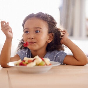 Niña vegetariana comiendo un plato de frutas