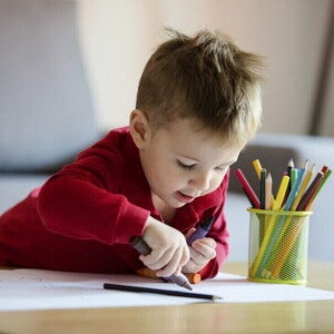 Niño pequeño coloreando una hoja blanca. Aprendiendo colores.