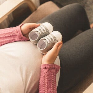 Conoce cómo es el bebé arcoíris. Mamá embarazada de un bebé arcoíris cogiendo unos zapatitos.