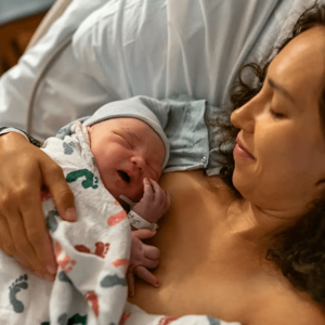 Mamá abrazando a su bebé en una cama de hospital luego de un parto por cesárea