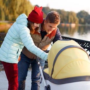Conoce los consejos para comprar la carriola para bebés. Mamá y papá mirando a su bebé en la carriola.