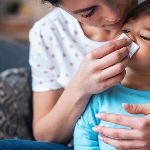 Es importante descongestionar la nariz de un bebé para su correcta respiración Mujer descongestionando la nariz de un bebé