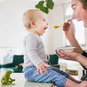 ¿Para qué sirven los probióticos? Mamá alimentando con una cuchara a su hijo pequeño con probióticos.