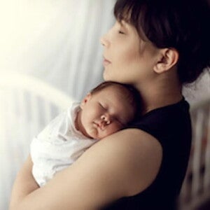 Mamá abrazando a bebé durmiendo en el periodo del puerperio. Cuidados para evitar complicaciones del puerperio