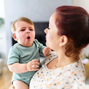 Mamá cargando a su bebé que tose. Asma en niños y bebés.