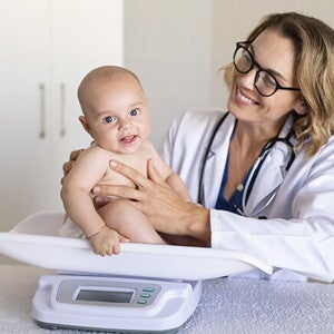 La tabla de peso en niños es una herramienta muy útil. Doctora pesando al bebé.