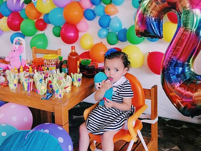 Snacks para su mejor desarrollo Pequeña sentada en una silla con globos a su alrededor disfrutando de Snacks para bebes