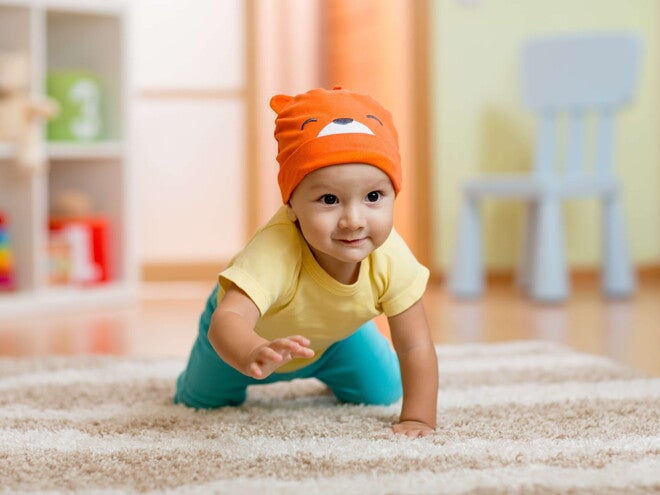 ¿A los cuántos meses gatea un bebé? Bebé gateando sobre alfombra.