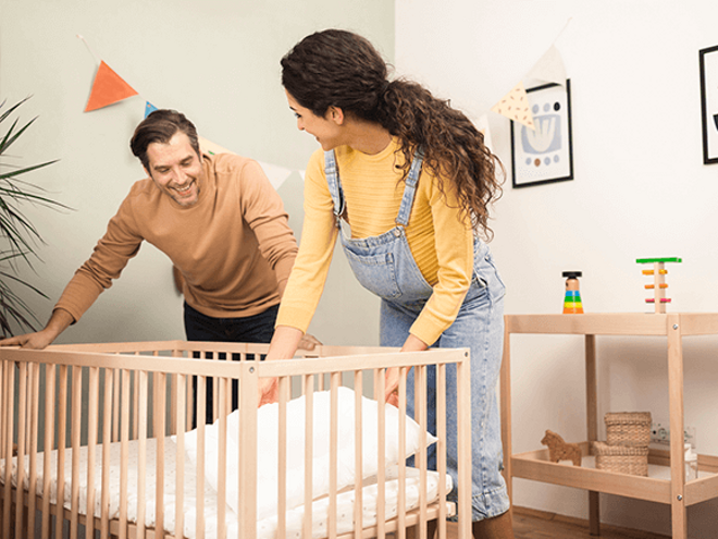 Preparate para la llegada de tu bebé con nuestra guía completa Un hombre y una mujer preparan la cuna del bebe
