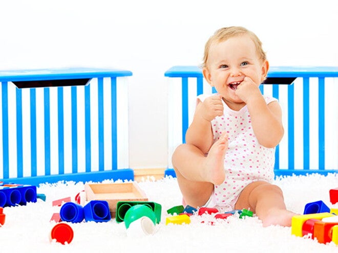 Es importante saber a los cuántos meses se sienta un bebé y acompañar este proceso Bebé sonriendo sentado al lado de sus juguetes