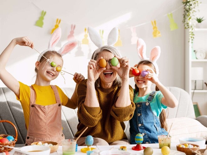 Padres y niños celebrando Pascua, cubriendo sus ojos con huevos de colores de forma divertida.