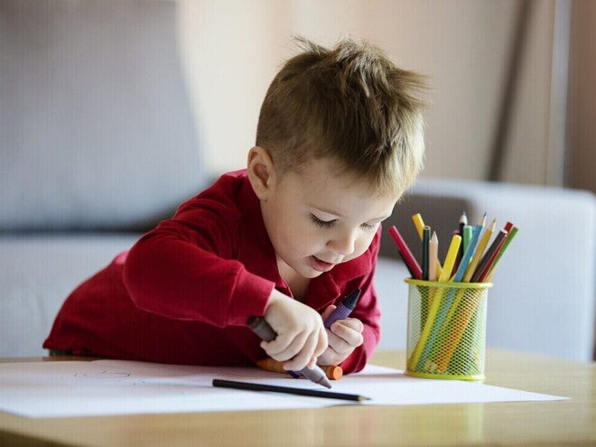 Niño pequeño coloreando una hoja blanca. Aprendiendo colores.