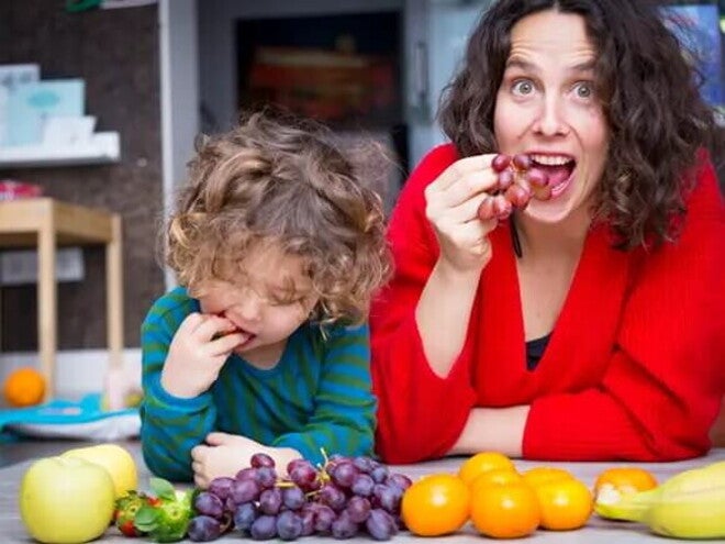 Mamá e hijo pequeño comiendo frutas con azúcar natural.