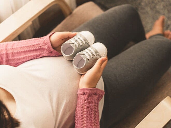 Conoce cómo es el bebé arcoíris. Mamá embarazada de un bebé arcoíris cogiendo unos zapatitos.