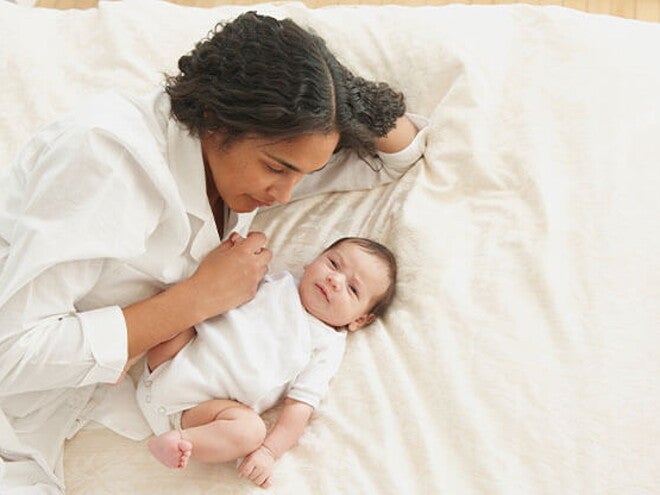 Conoce el desarrollo de un bebé de 3 meses Mamá acostada en la cama con su bebé de 3 meses.