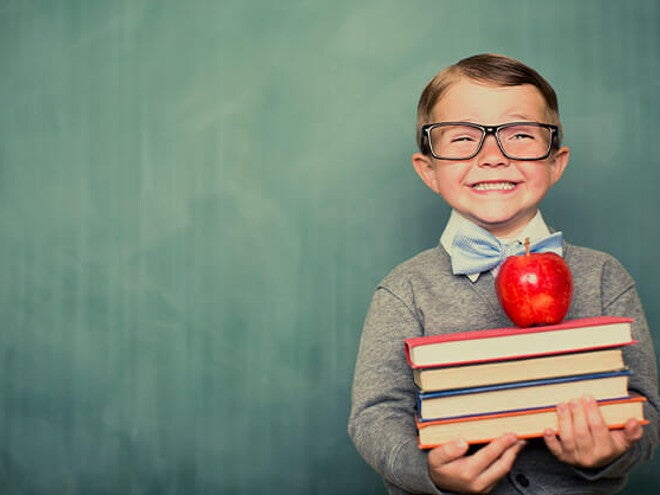 Conoce qué son las estrategias de aprendizaje. Niño sonriendo con libros en la mano.