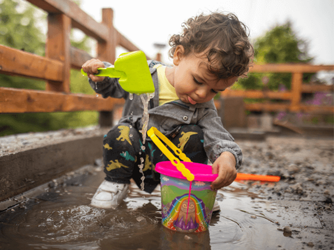 Niño con buen sistema inmune jugando Niño con buen sistema inmunológico jugando con agua en el lodo