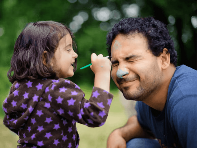 Técnicas para amamantar a tu bebé Niña pequeña pintando la cara de su papá, jugando y sonriendo.