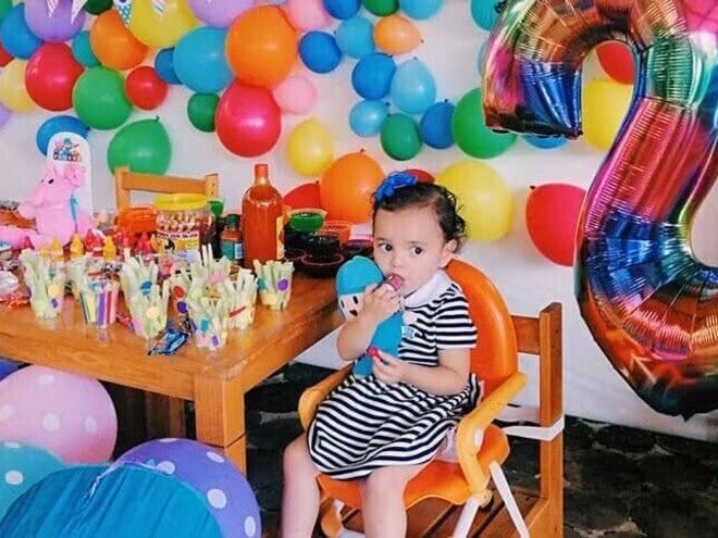 Pequeña sentada en una silla con globos a su alrededor disfrutando de Snacks para bebes