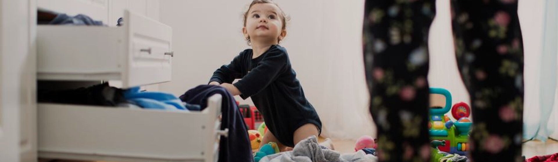 young child looking through clothes drawers