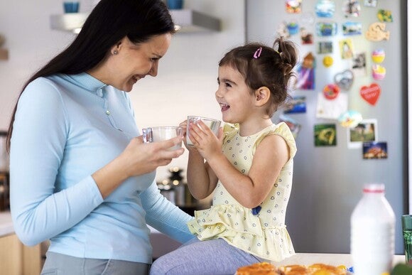 Familia con una niña compartiendo una comida en casa, sentados en la cocina y disfrutando juntos.