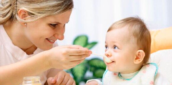 La alimentación es importante para un bebé de 6 meses Un bebé de 6 meses siendo alimentado por su madre
