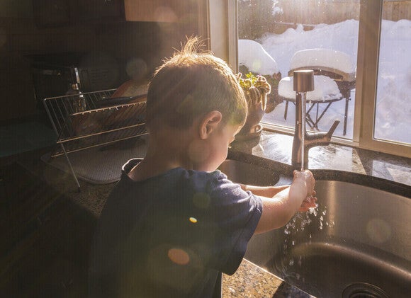Niño pequeño lavándose las manos para prevenir la estomatitis infantil