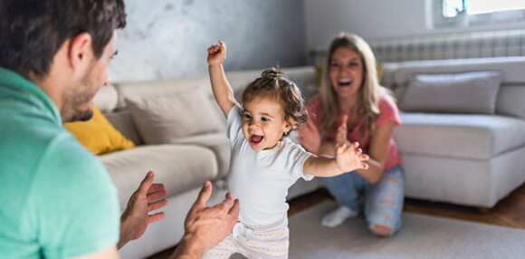 Conoce los síntomas de la displasia de cadera. Papá y mamá viendo cómo camina la hija.