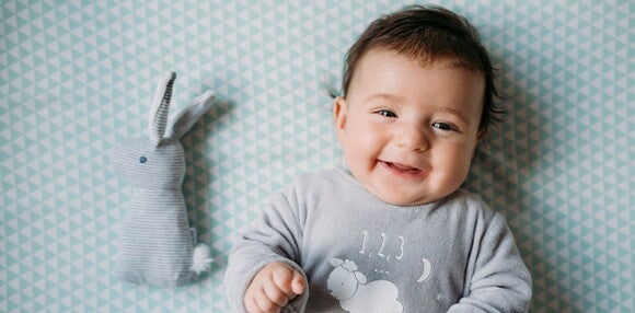 Los bebés de cuatro meses tienen mayor control de su cabeza y extremidades Bebé de cuatro meses sonriendo