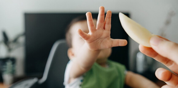 Es importante buscar alternativas para que sea más fácil la ingesta de las frutas en los bebés. Niño recibiendo un trozo de fruta con su mano.