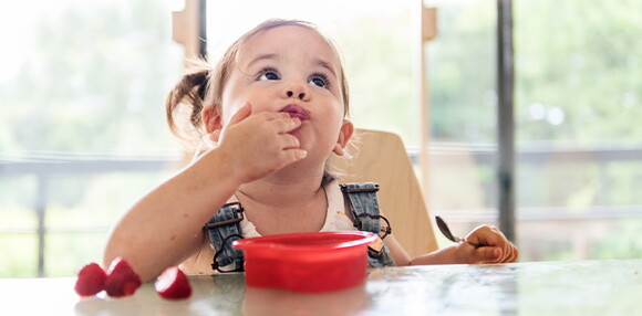 Prueba qué frutas pueden comer los bebés dándole una cada día e identificando sus gustos. Niña comiendo fresa.