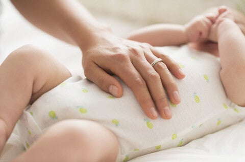 Mamá masajeando la pancita de su bebé con molestias digestivas como cólicos, reflujo, gases y estreñimiento.